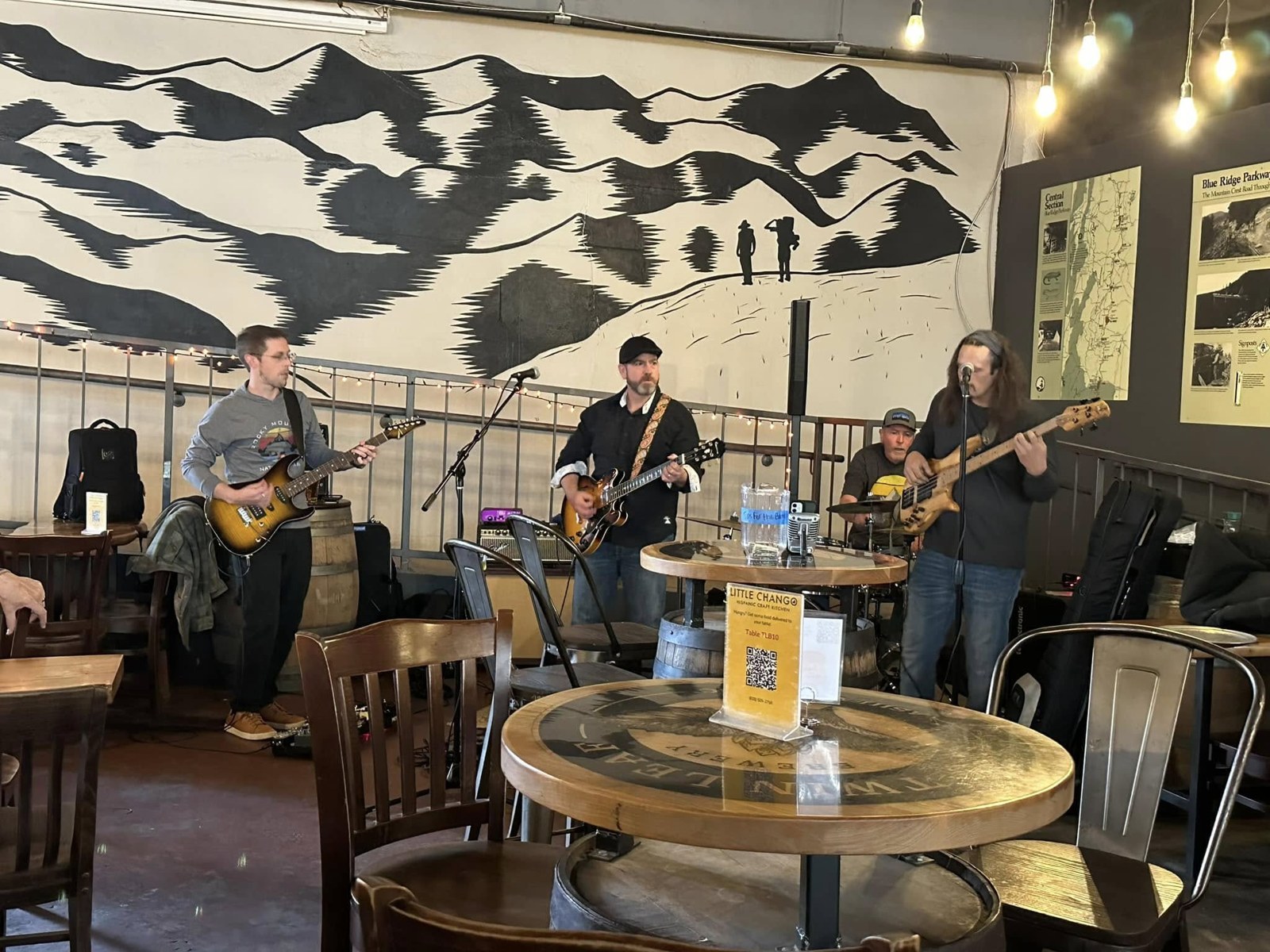Mama Roux performing live at a brewery in front of a Blue Ridge mural